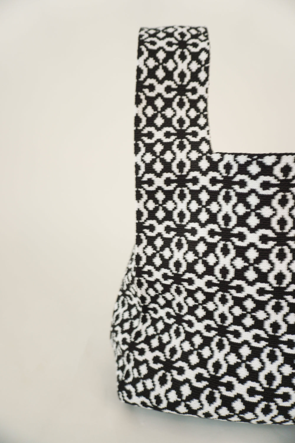 Black Solitaire handbag, side view of structured drawstring pouch with geometric pattern