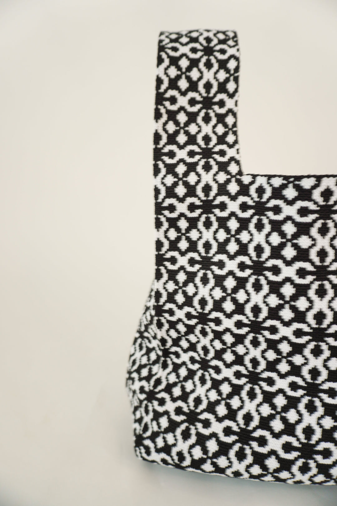 Black Solitaire handbag, side view of structured drawstring pouch with geometric pattern