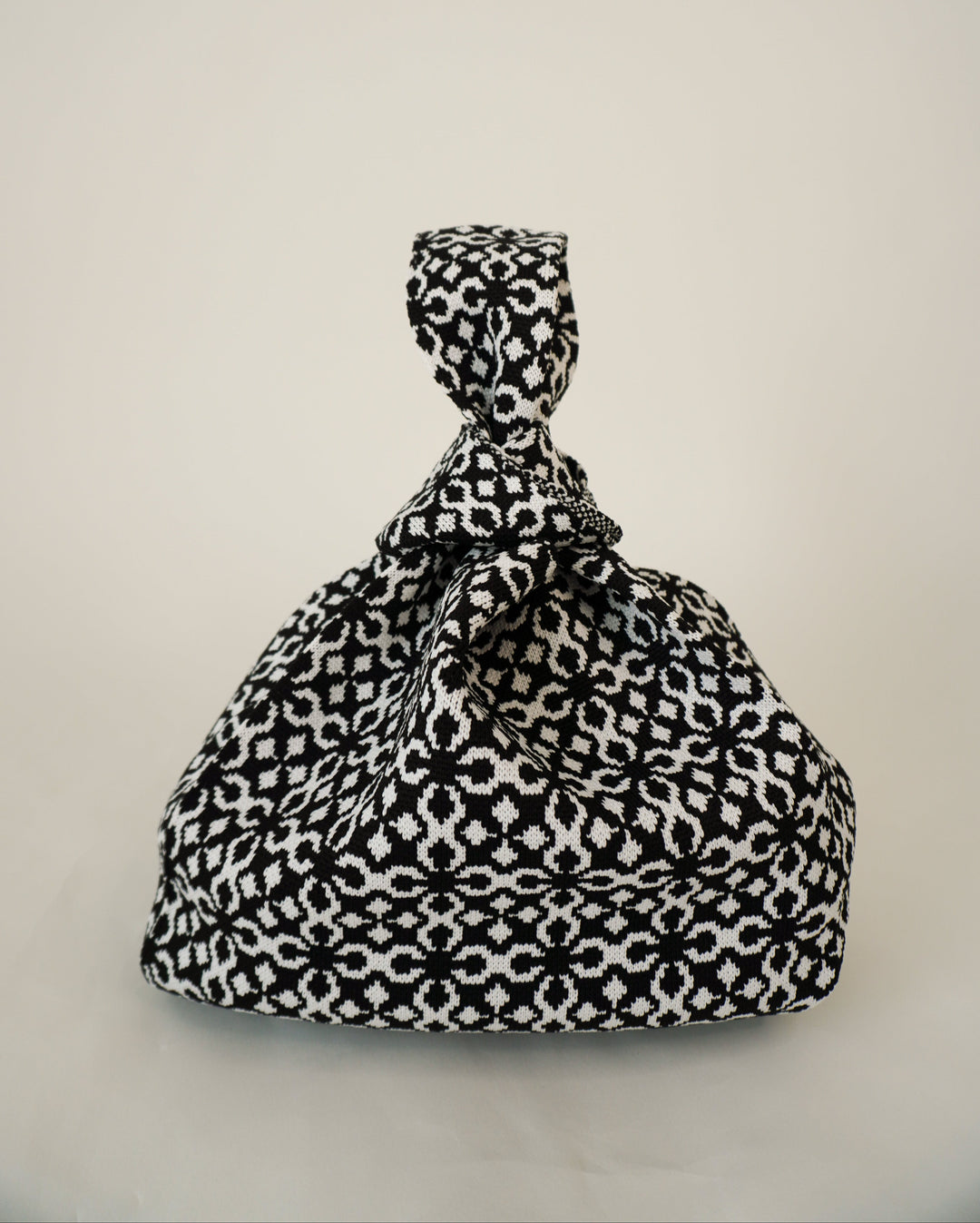 Black Solitaire handbag with bow-top drawstring and black-and-white geometric print