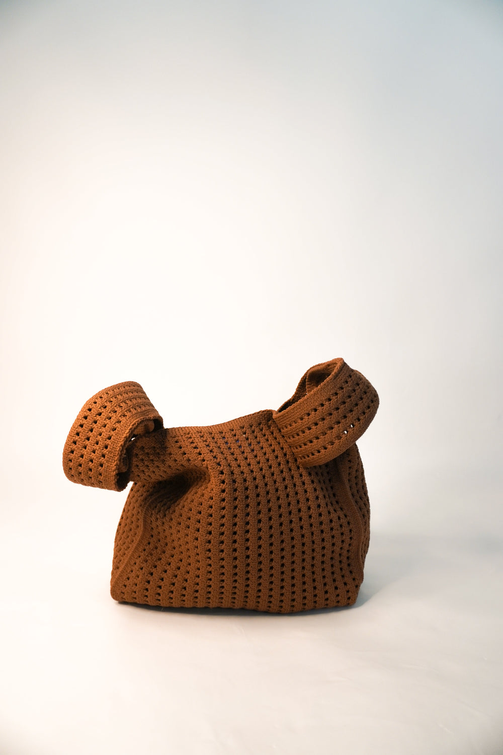 Brown crochet bucket handbag with two short loop handles and perforated knit