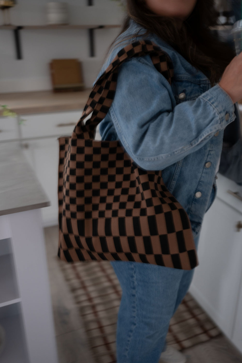 Skinny tote bag with black trim, brown-and-black checkered pattern, and wide carry handles.