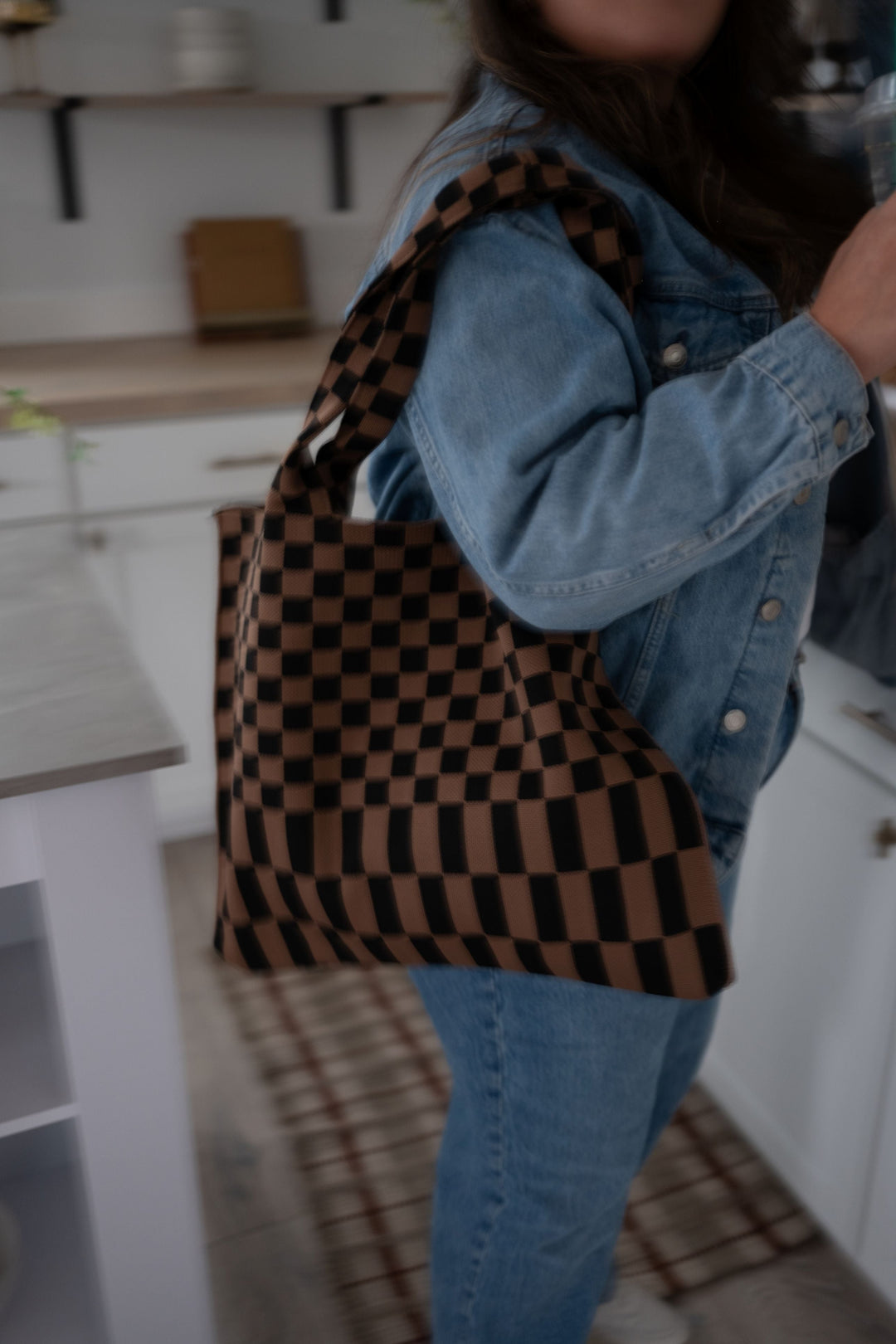 Skinny tote bag with black trim, brown-and-black checkered pattern, and wide carry handles.