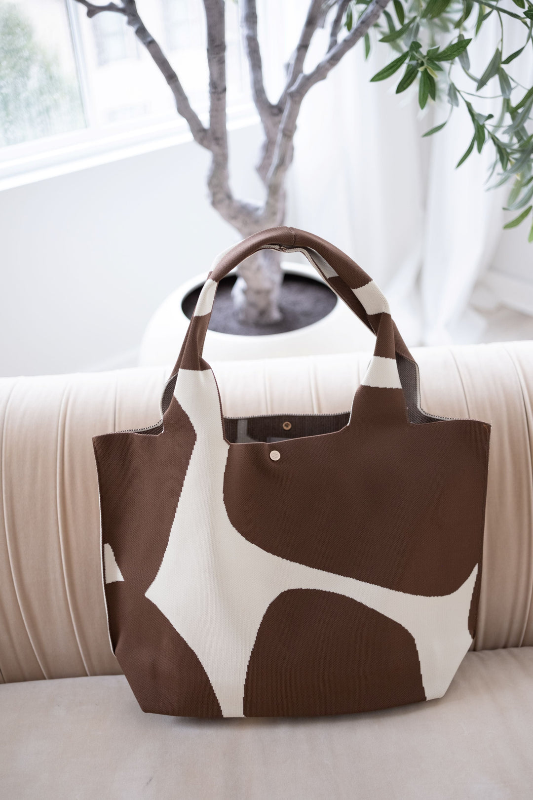 Brown tote with cream abstract design, reinforced handles, snap button at top