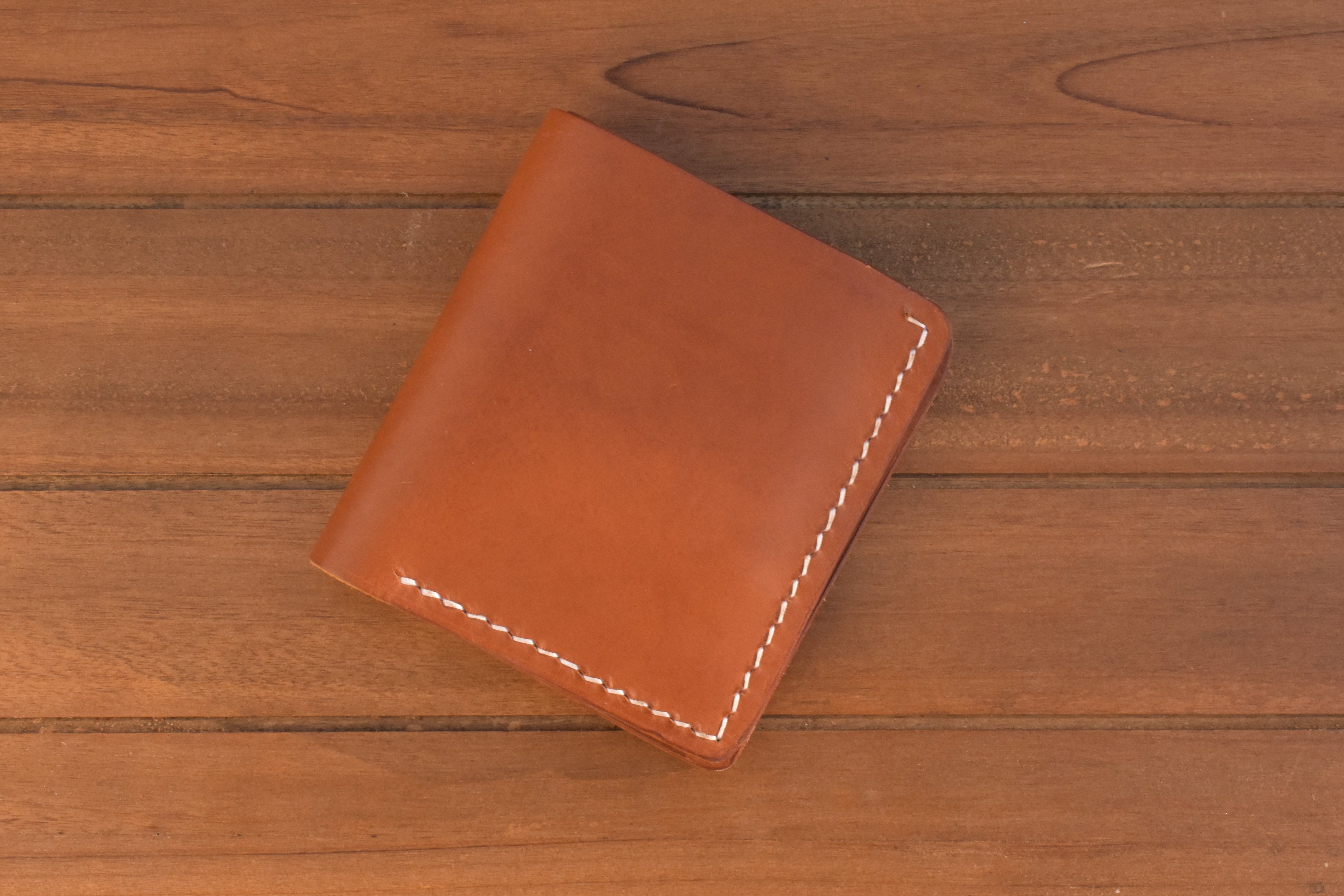 ID bi-fold wallet in brown leather with white stitching, closed front view