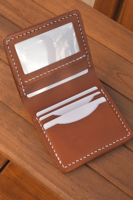 ID bi-fold wallet open view: ID window and card slots, brown leather with white stitching