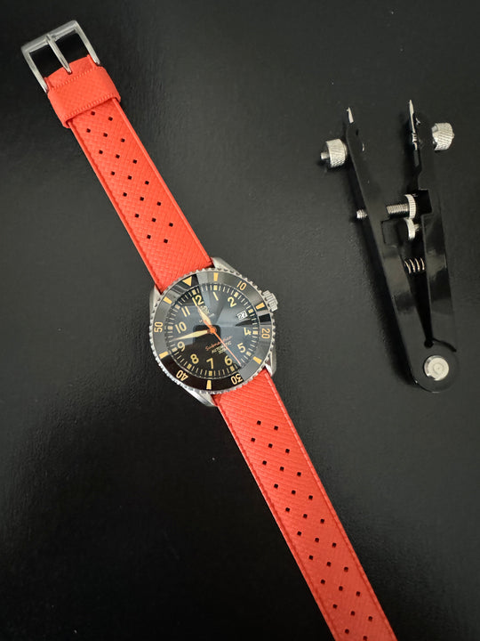 Tropic Bands watch with orange-red perforated strap and silver buckle, black dial