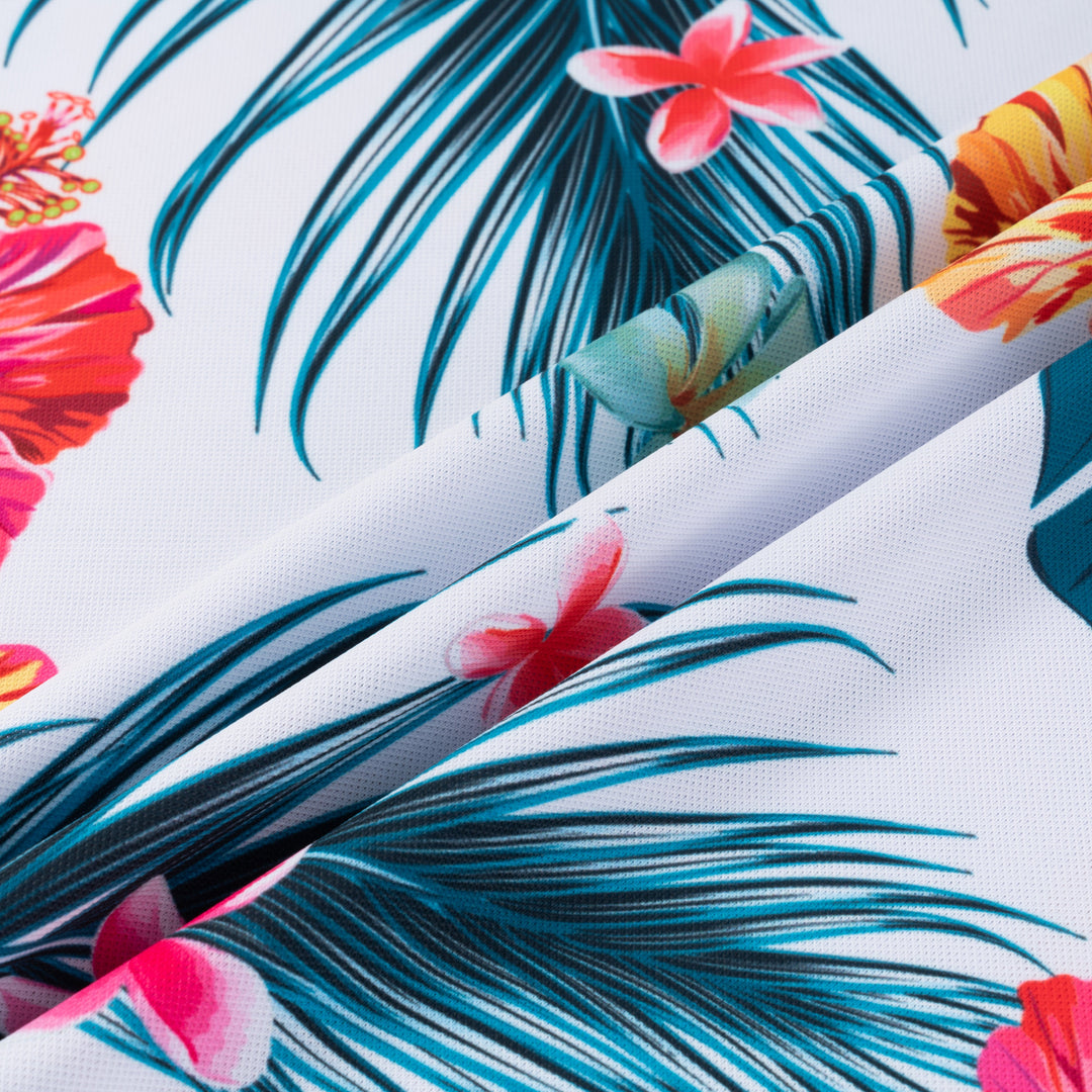 Close-up Hawaiian floral fabric: teal palm leaves and pink flowers on white