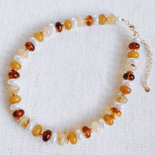 Warm-toned bead necklace flat; white, orange, amber mix with gold extender chain