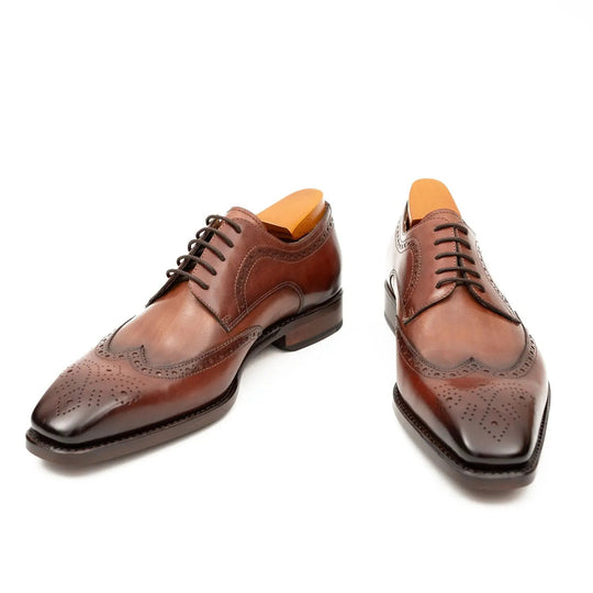 Brown brogue derby shoes, front view with wing-tip pattern and lace-up