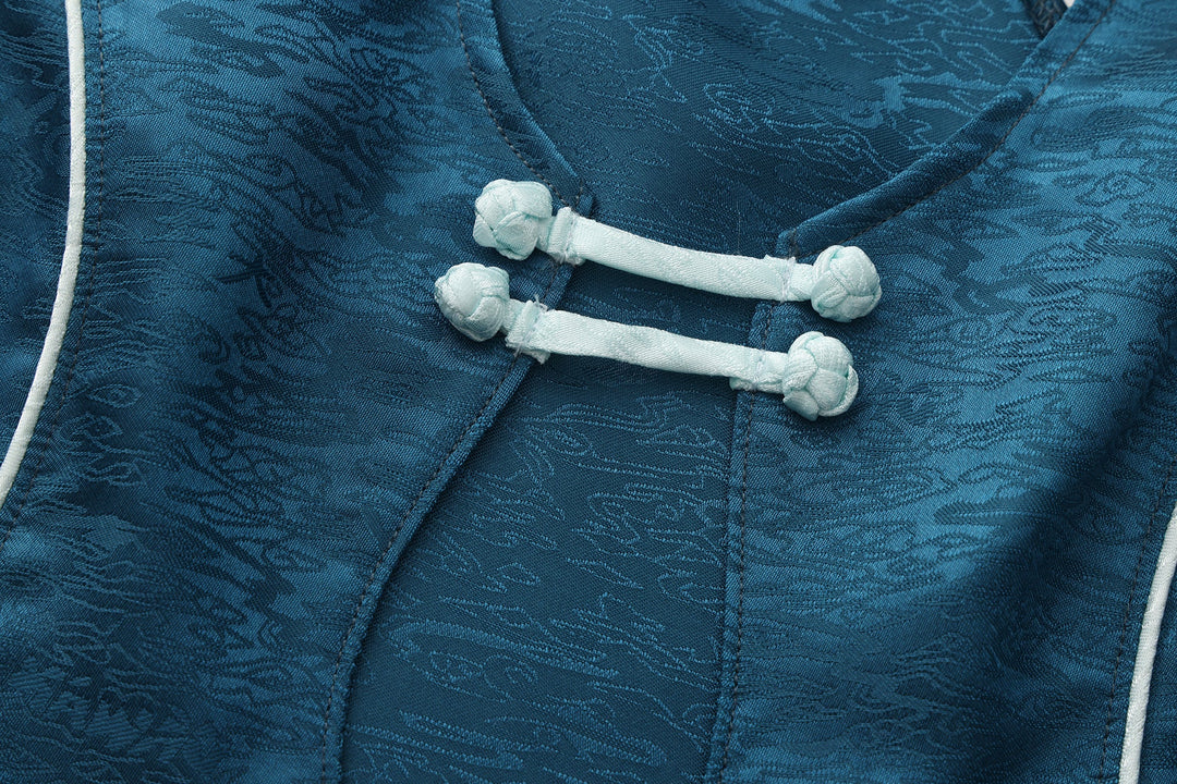 Close-up of forest blue top neckline tie with white cord and pom-pom hardware