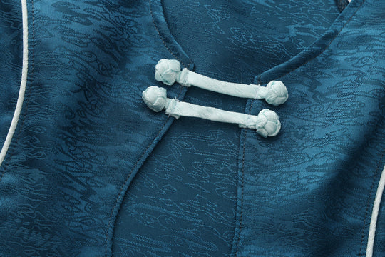 Close-up of forest blue top neckline tie with white cord and pom-pom hardware