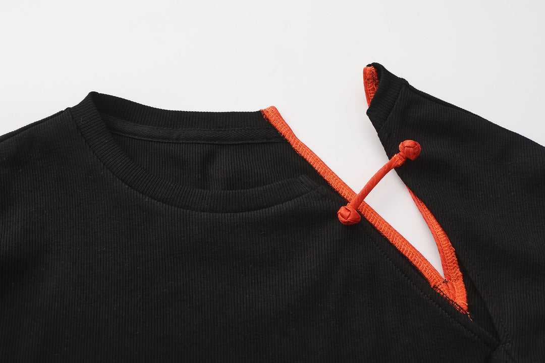 Close-up: black knit top with orange strappy cutout and tie at neckline.