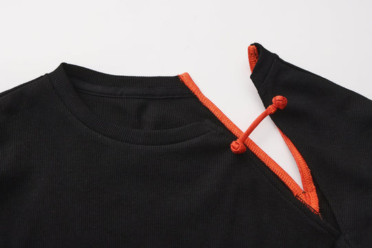 Close-up: black knit top with orange strappy cutout and tie at neckline.