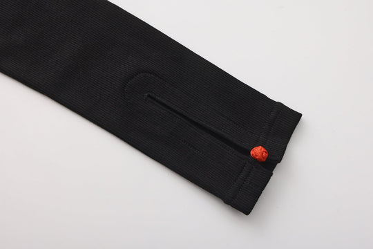 Close-up of black long-sleeve cuff with ribbed texture and small orange button
