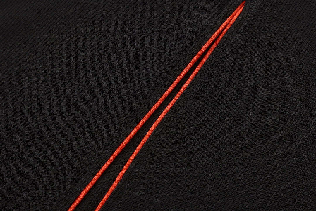 Orange-trim piping along seam on black ribbed maxi dress