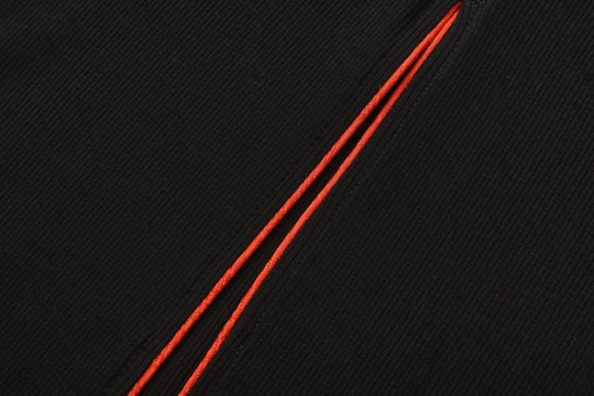 Orange-trim piping along seam on black ribbed maxi dress