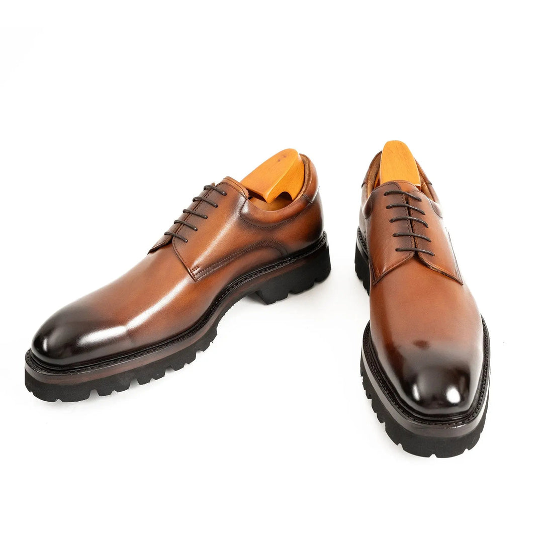 Brown derby shoes from the side and front, lace-up and dark stitched trim