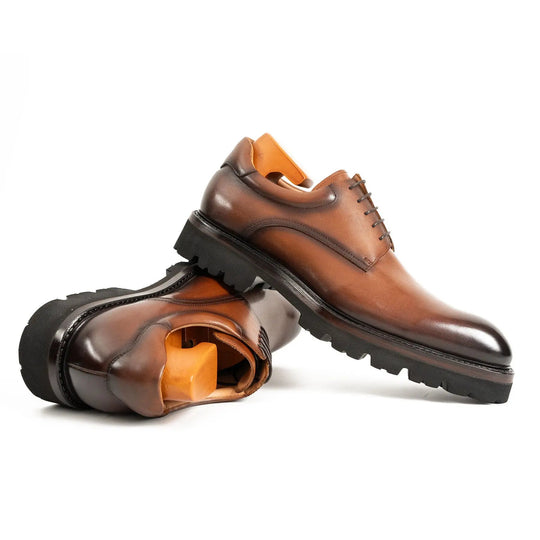 Brown leather derby shoes, one shoe turned to show the inside opening