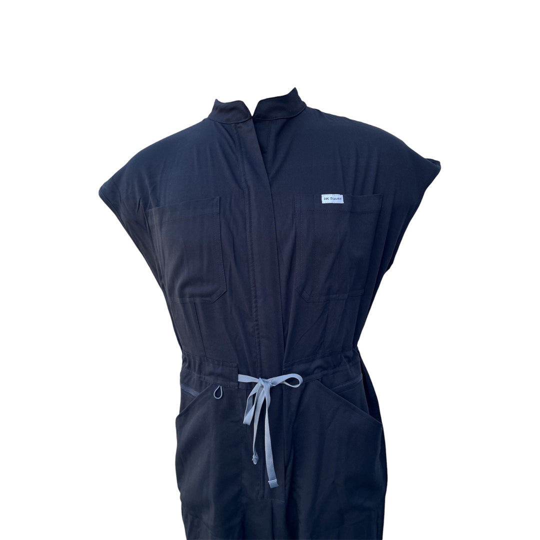 Black scrub jumpsuit detail: front zip placket, patch pockets, drawstring waist ties.