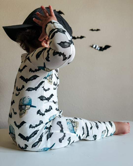 Back view of zippy pajamas: hood and long sleeves, white with black bats and blue skulls