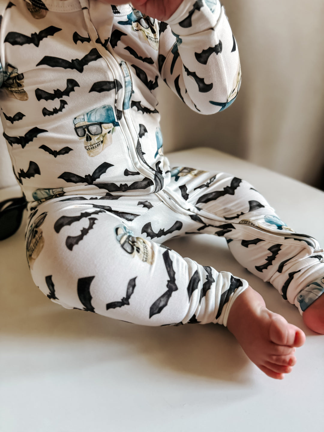 Close-up: zip-front bamboo pajamas in white with bats and blue skulls all over