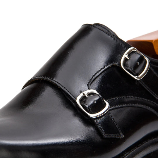 Close-up of black double monk straps with two silver-tone buckles on the vamp