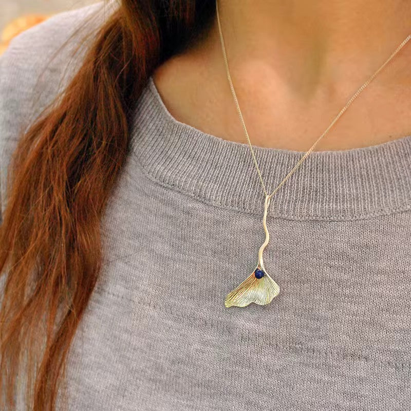 Ginkgo Elegance Pendant, gold leaf design with blue bead, fine chain on sweater
