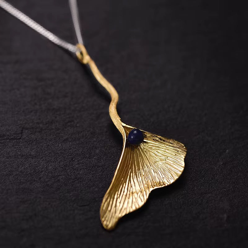 Ginkgo Elegance Pendant close-up: gold ginkgo leaf, blue bead, wavy bail