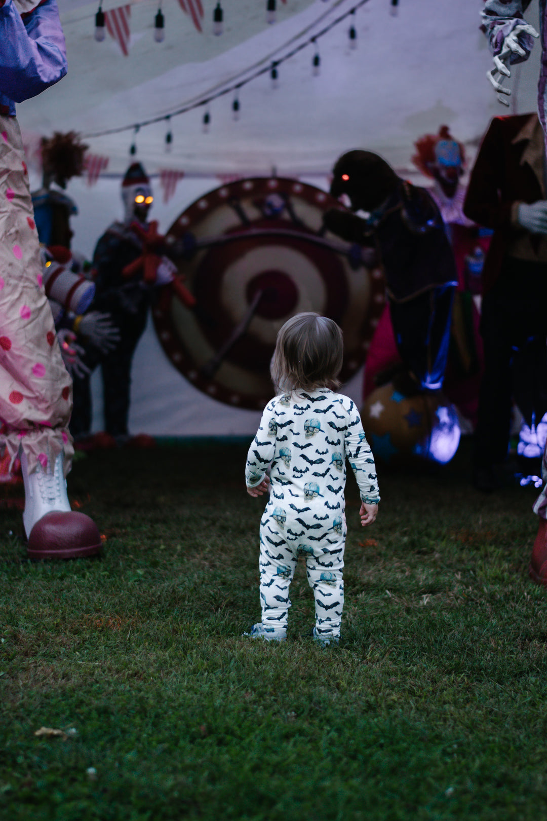 Toddler wearing spooky zippy pajamas in white with black bats and blue skull prints