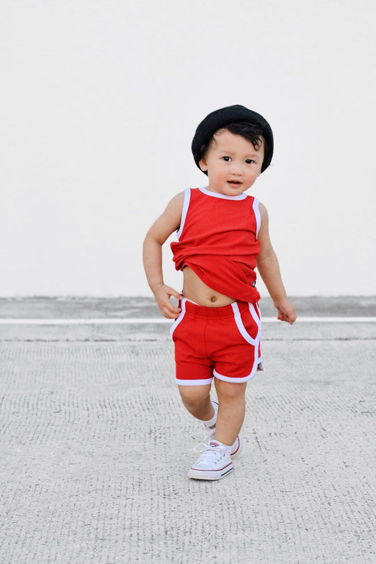 Red sleeveless track top and shorts with white trim and stitched striped side panels