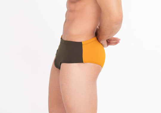 Rear side view of athletic swim brief: orange waistband panel and dark seat panel