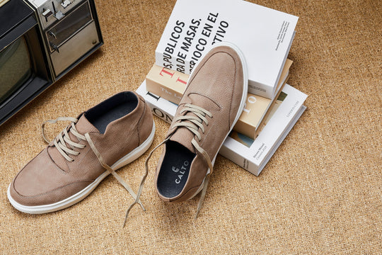 Khaki lace-up boots on floor with shoeboxes beside them