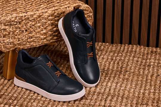 Navy slip-on sneakers with tan pull tab and orange lace-look stripes