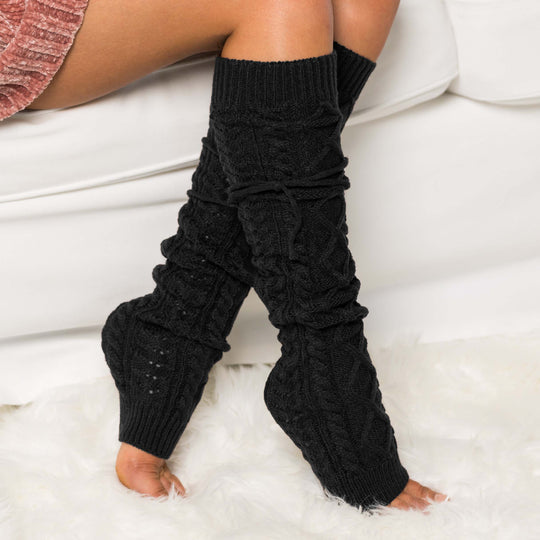 Long cable-knit leg warmers in black with raised cable stitches and ruffled cuffs