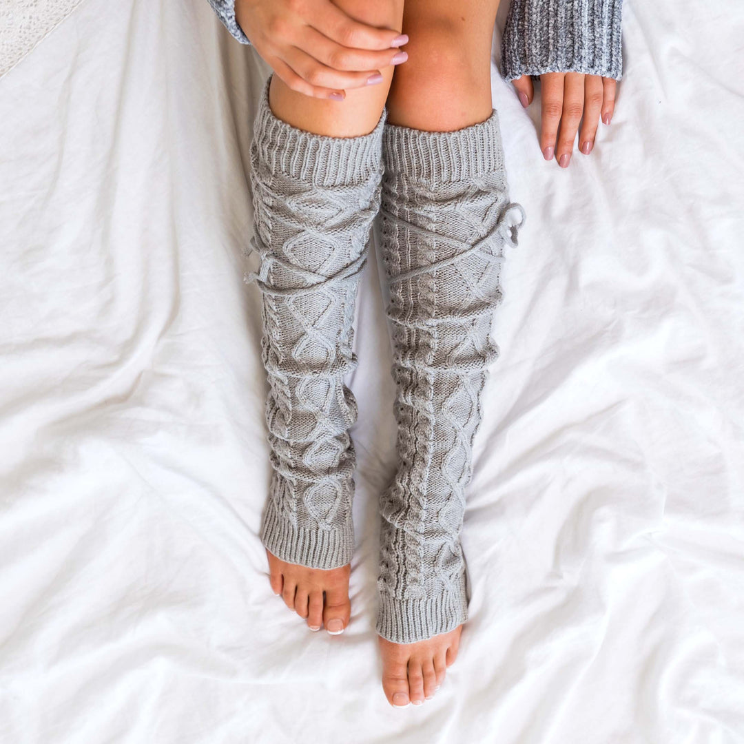 Long cable-knit leg warmers in light gray with detailed cable and diamond stitching