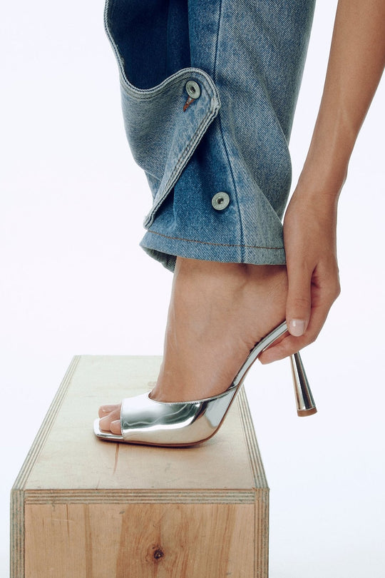 Greta Mule 70 Spiegel-Leder, offene Zehen, hoher schmaler Absatz unter Jeansbein