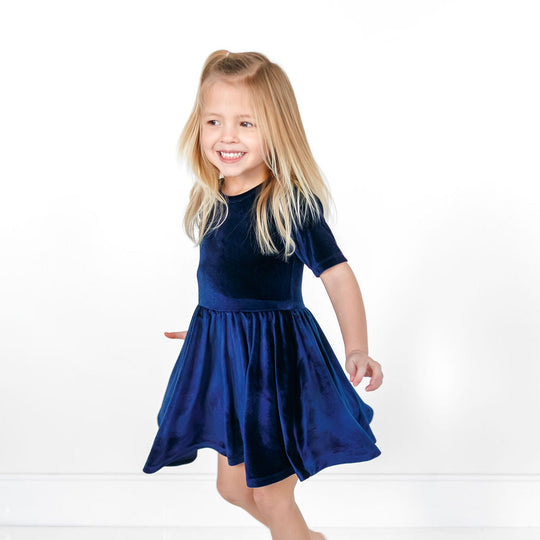Navy velvet twirl dress with short sleeves and flared gathered skirt on model