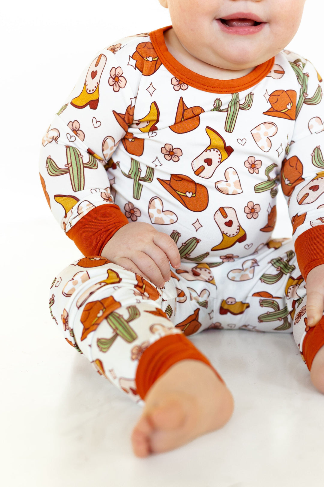 Close-up of long-sleeve baby top in white with orange neckline and matching cuffs