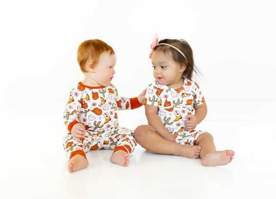 Two-piece long-sleeve set on babies, white fabric with orange cuffs and woodland cactus print