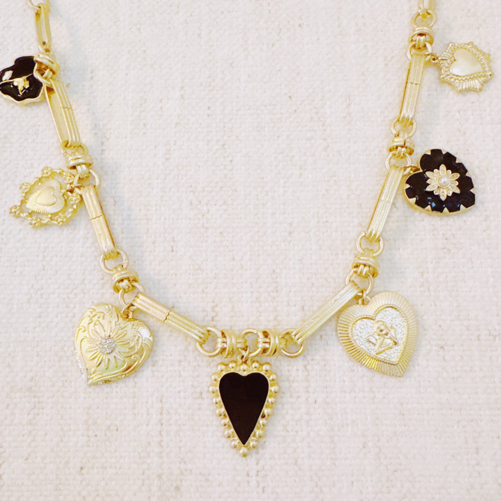 Gold-tone heart charm necklace with black and gold pendants, shown straight on a chain