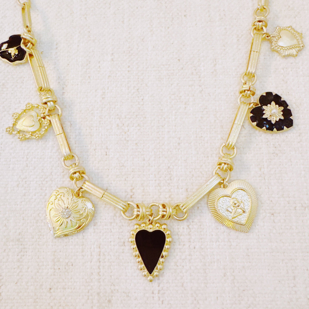 Gold-tone heart charm necklace with black and gold pendants, shown straight on a chain
