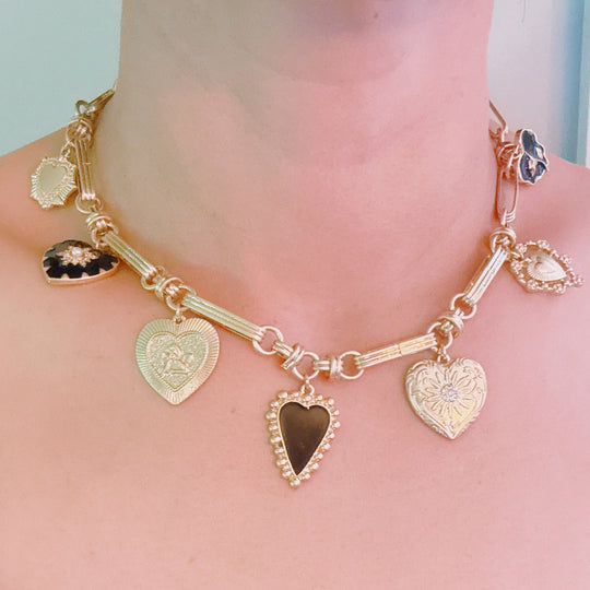 Gold-tone heart charm necklace on model’s neck with black and gold heart pendants