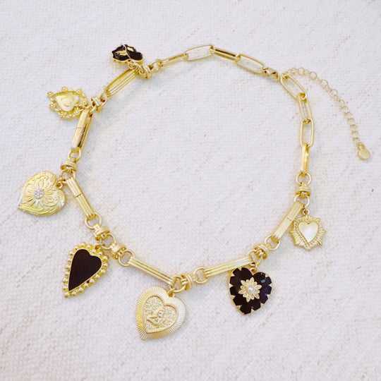 Gold-tone charm bracelet with mixed black and gold heart pendants and link design