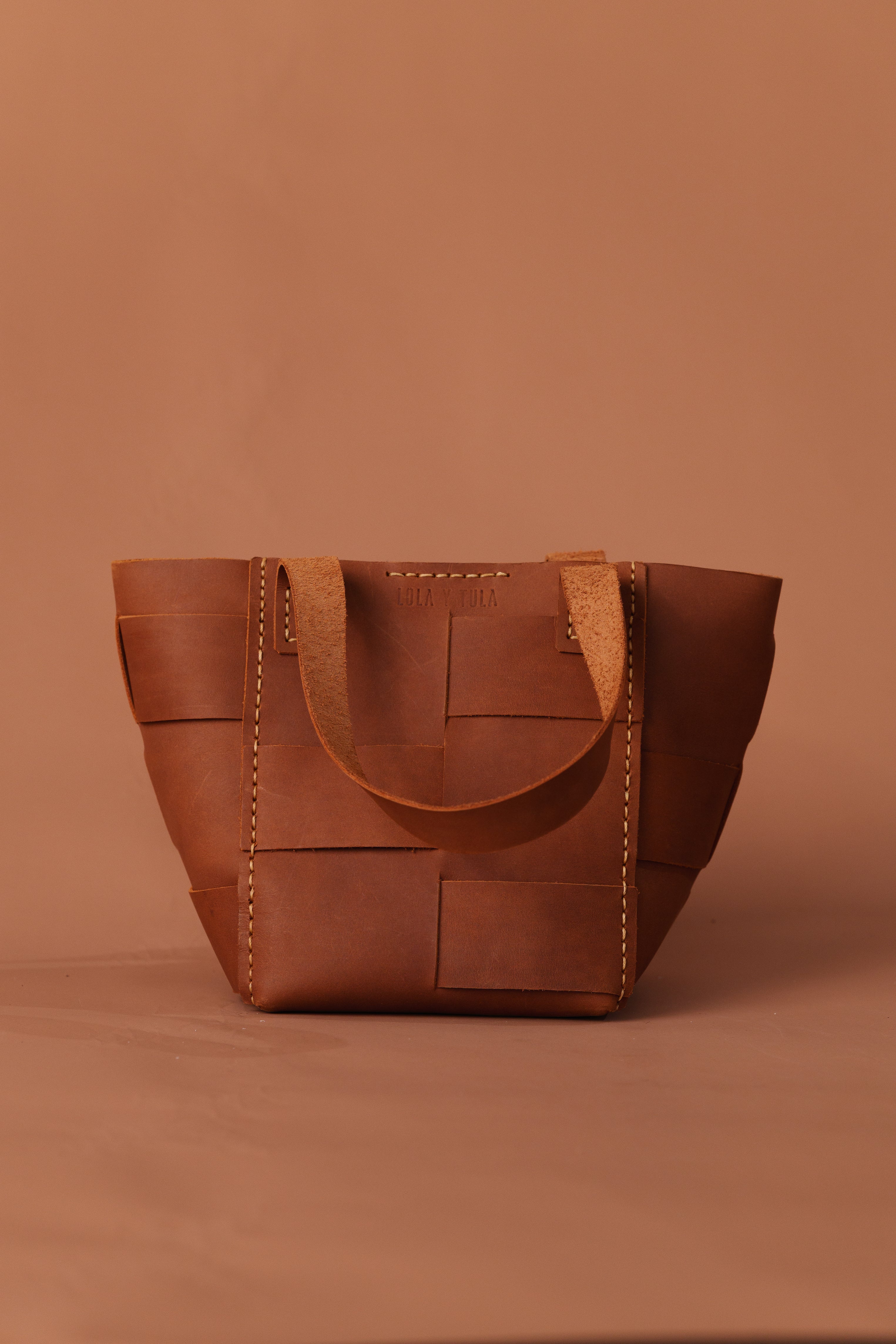 Camel basket tote with top curved flap and stitched handles, square front pocket