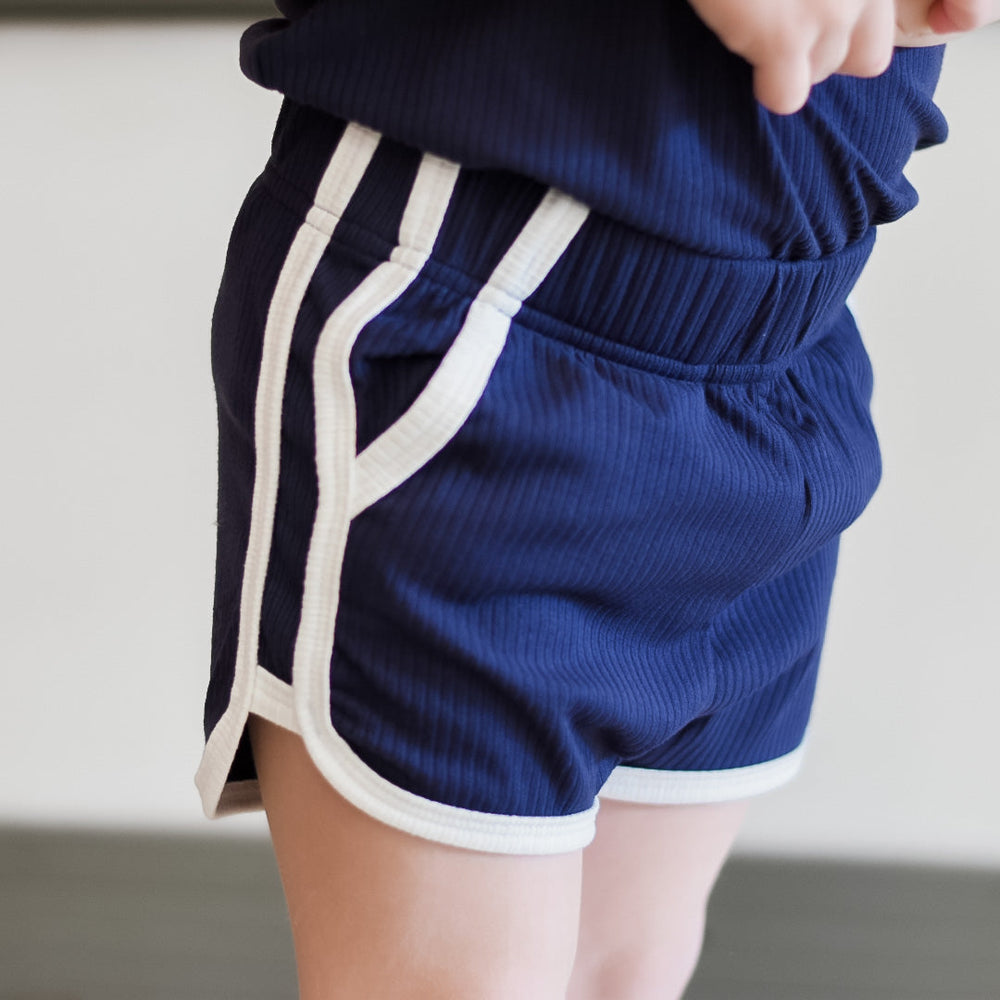 Navy track shorts with white side piping and ribbed knit waistband detail