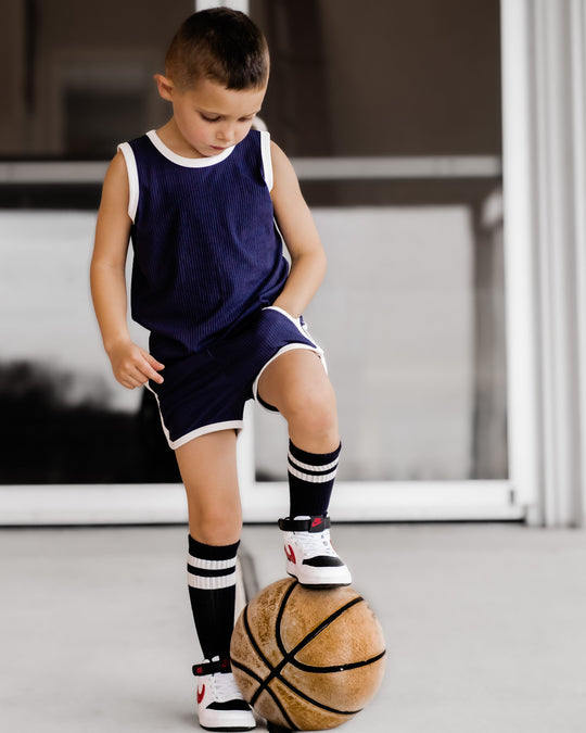 Navy track shorts set shown from side: sleeveless tank, striped trim shorts