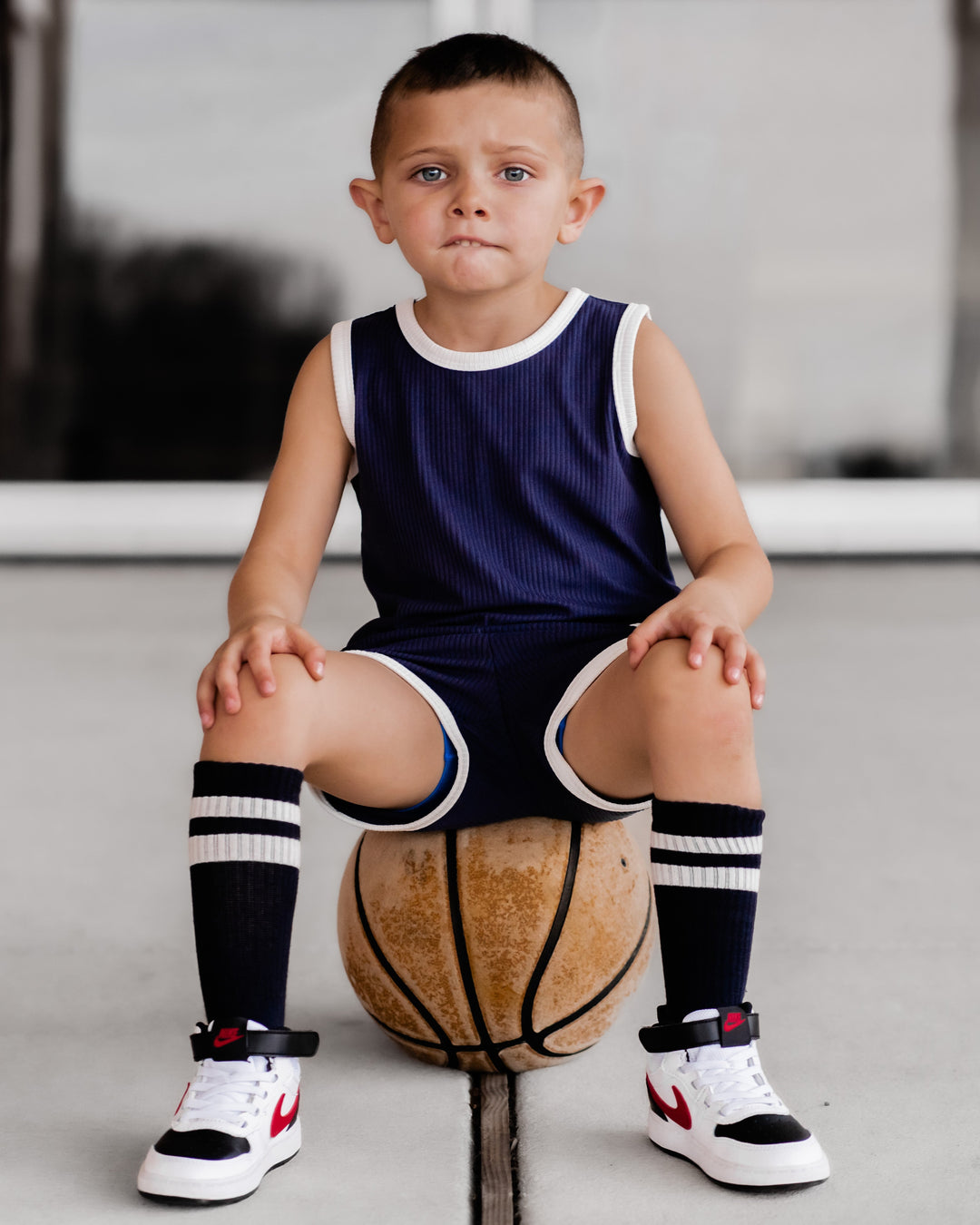 Navy sleeveless top and shorts set with white trim and ribbed texture, kneeling view
