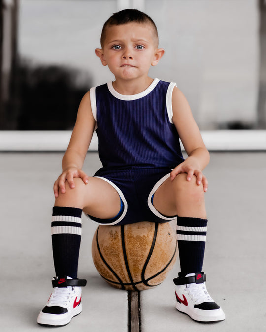 Navy sleeveless top and shorts set with white trim and ribbed texture, kneeling view