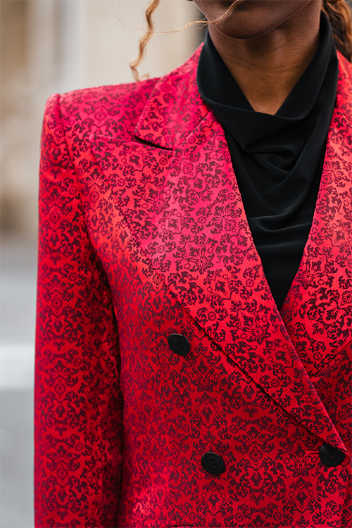 Red patterned blazer sleeve and lapel detail with black shirt collar and buttons