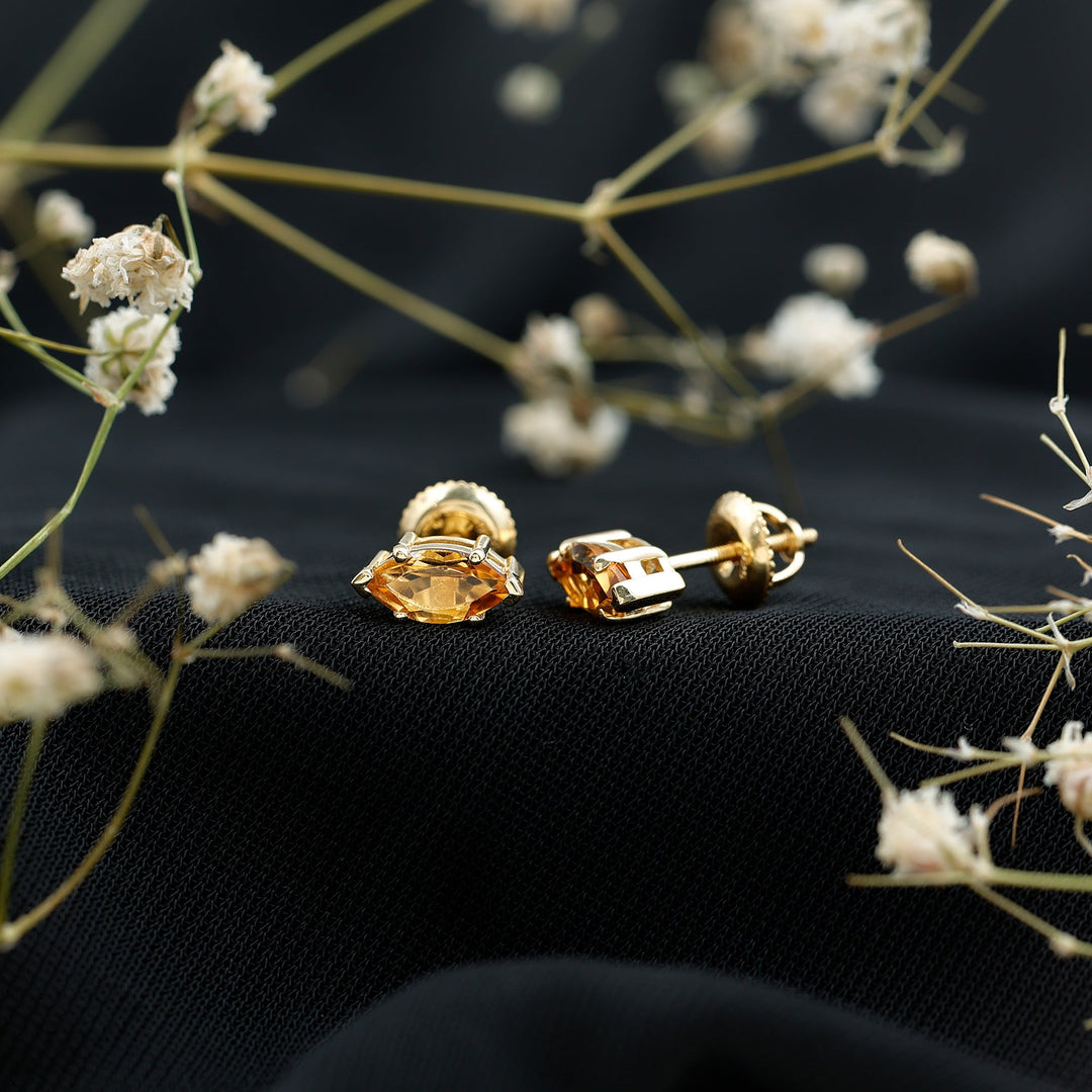 Citrine marquise stud earrings on dark mesh background, gold-tone settings